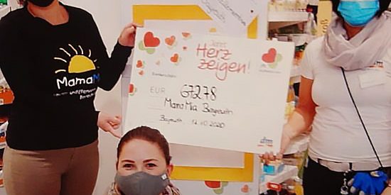 Scheck gehalten von Mama Mia Mitarbeiterin und DM-Mitarbeiterin