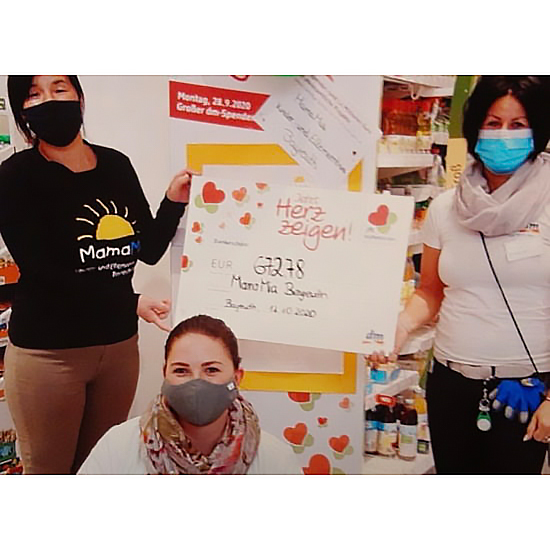 Scheck gehalten von Mama Mia Mitarbeiterin und DM-Mitarbeiterin